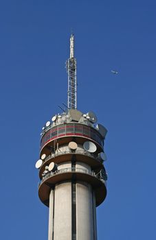 Telecom tower with airplane in the sky