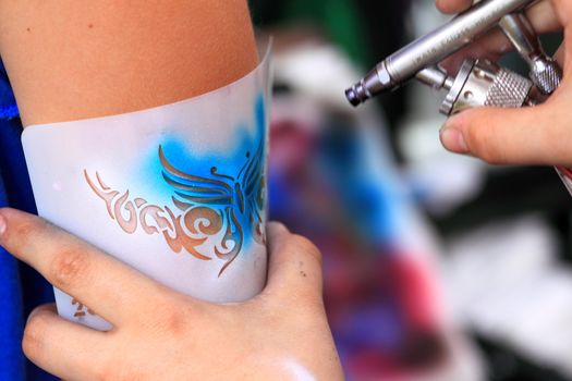 creating an air brush tatoo on a youn gilrs arm