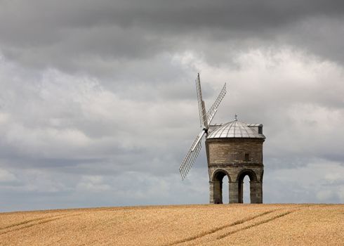 An old stone windmill standing in a cornfield.