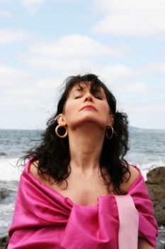 beautiful woman meditating on the rocks in ireland with her eyes closed, in the lotus position, showing a healthy way to live a happy and relaxed lifestyle in a world full of stress