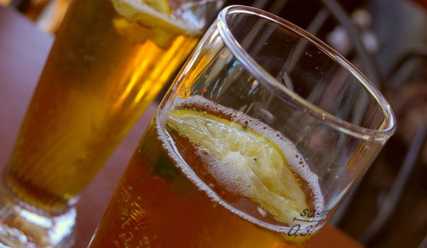 closeup of glass of cold beer with slice of lemon