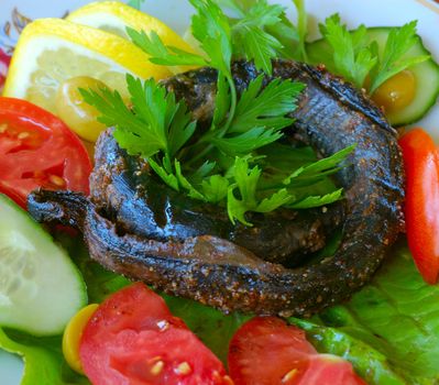 asian food - fried stone eel (lamprey, snake-like fish) and vegetables