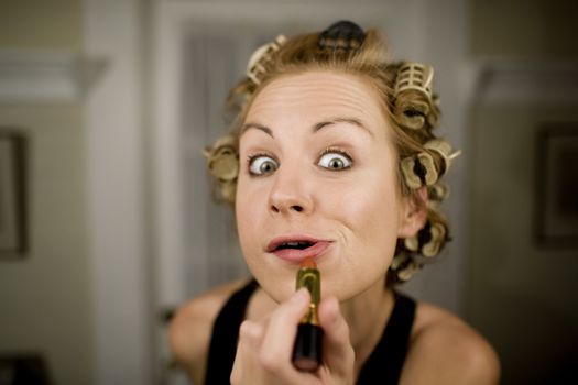 Woman in Curlers Applying Bright Red Lipstick