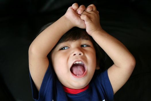 Adorable toddler boy lifting arms over head cheering. Part Scandinavian, Thai descent