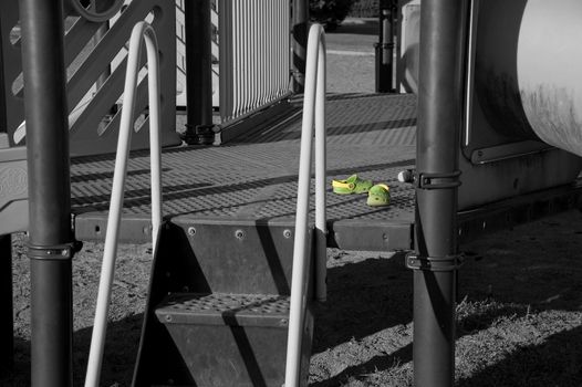 A pair of green kid's shoes on the playground, only the shoes are color.