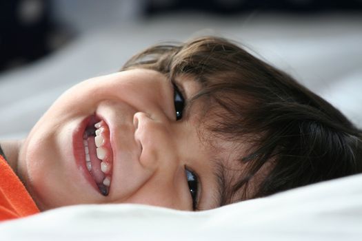 Happy little toddler boy lying down and smiling