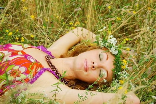 Beautiful girl with flower diadem lying in grass