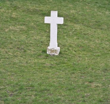 A white cross in a green grass field.