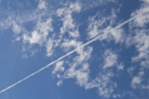 Airplane traces over a blue cloudy sky 