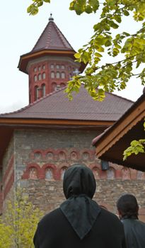 Image of a nun praying in front of a Romanian Monastery.