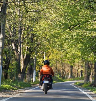 Image of a person riding a scooter in a summer park.Shot with Canon 70-200mm f/2.8L IS USM