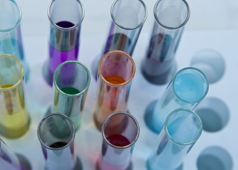 Upper view of some testtubes with colorful solutions in a stand.