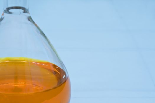 Detail image of a lab flask containing an orange solution (soft focus)