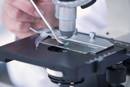 Detail of analyzing a blue substance with a microscope.Selective focus on the blue dust.