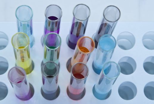 Upper view of some testtubes with colorful solutions in a stand.