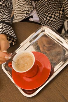 Detail view of a woman's hand mixing the sugar in a coffee cup. 