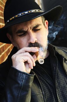 Man with beard in cowboy hat smoking cigar