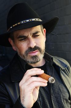 Man with beard in cowboy hat smoking cigar