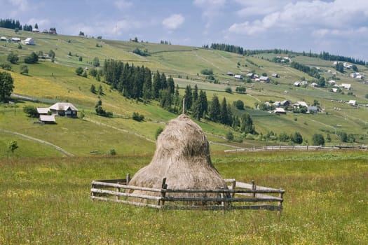 Romanian mountain village with a hay rick in the central first plane. Location: The Apuseni Mountains, Transylvania.