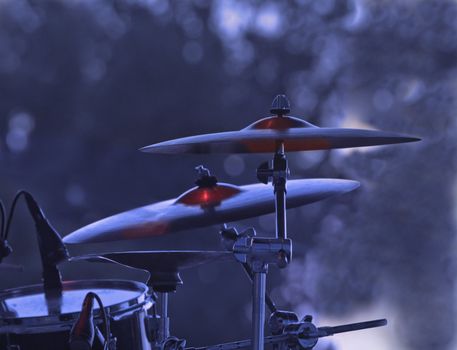 Image of cymblas and drum during a rock concert with specific lighting.
