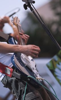Close-up image of a guitarist's hands while he is playing an electric guitar. 