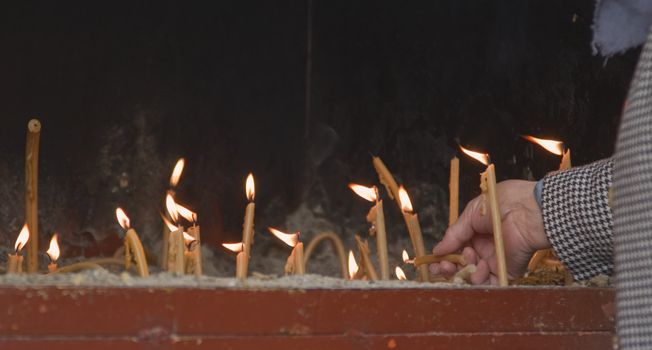 Old woman lighting candles in remembranse of the departed ones