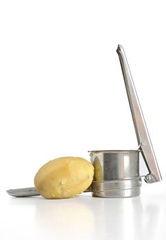 closeup of potato masher with two boiled potatoes isolated on white background with clipping path