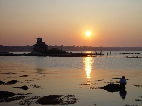 A fisherman enjoys an evening of fishing on the river.