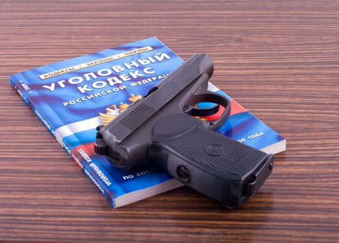 The criminal code of the Russian federation and pistol on a desk.