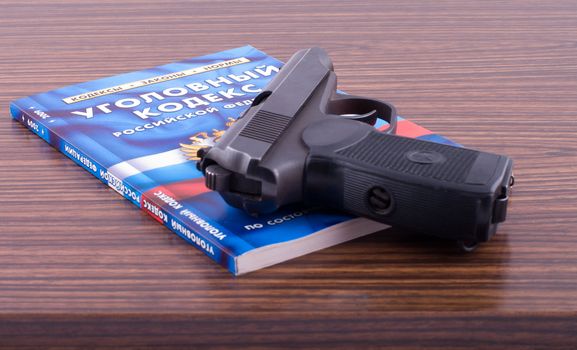 The criminal code of the Russian federation and pistol on a desk.