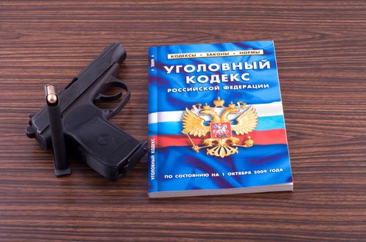 The criminal code of the Russian federation and pistol on a desk.