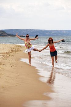 Two girls run on coast. Bulgaria. Gold sand