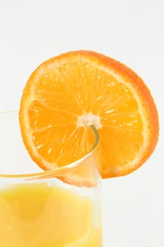 A glass of orange juice with an orange slice on the glass.
