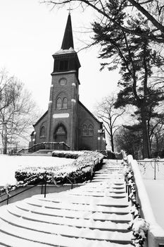 This old church sits on a hill and is blaneted by winter snow.