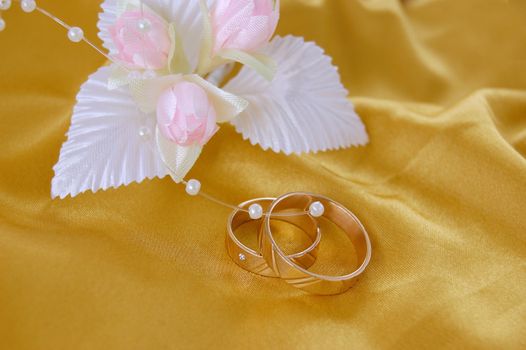 wedding golden rings with decoration on golden satin