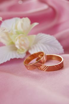 wedding golden rings with decoration on pink satin