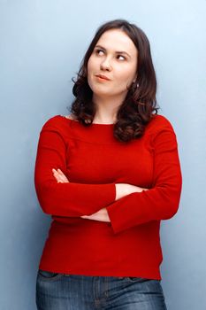 Young woman  in red jersey looking away with her hands folded 