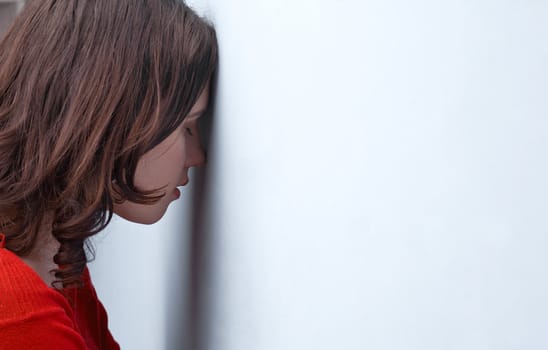 Tensed young woman leaning on a wall 