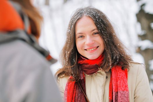 Smiling beautiful young woman with long brown hair in snow, outside on snowy day