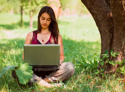 Happy young woman using her laptop outdoors.