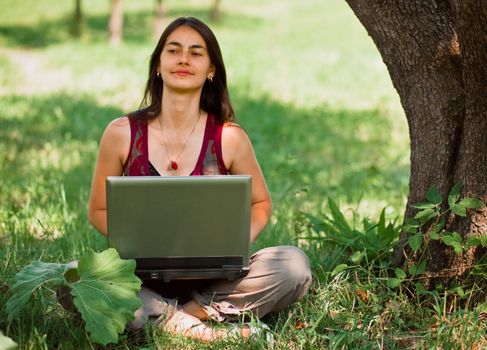 Happy young woman using her laptop outdoors.