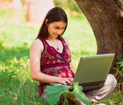 Happy young woman using her laptop outdoors.