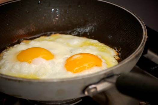 cooking two fried eggs in a pan, closeup