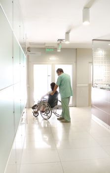 Nurse and a patient using a wheelchair at a hospital hall