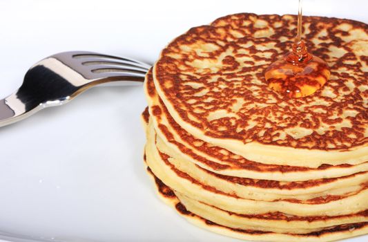 pile of american pancakes with syrup poured on them