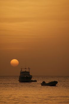 Two boats in front of a setting sun at dusk