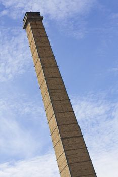 Nineteenth century brick gasworks chimney against blue sky and white clouds in Athens, Greece.