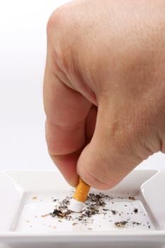 Hand stubbing out a cigarette on white ashtray isolated on white