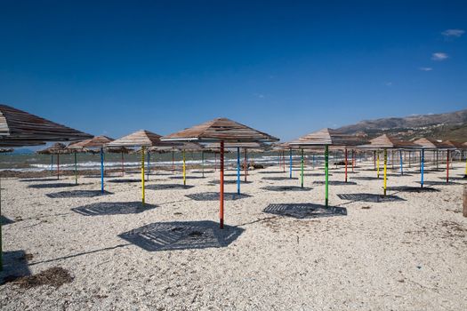 Set of beach umbrellas on sand making shadows under the blue clear sky in hot day