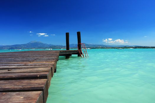 a small jetty in lake Garda Italy, fantastic color in the water and sky. Perfect for concepts of vacation or holidays